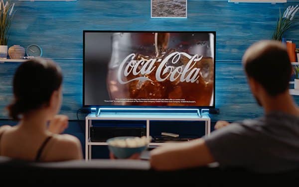 A couple watching a Cola-Cola advertisement on TV